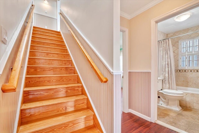 stairs with crown molding and wood finished floors
