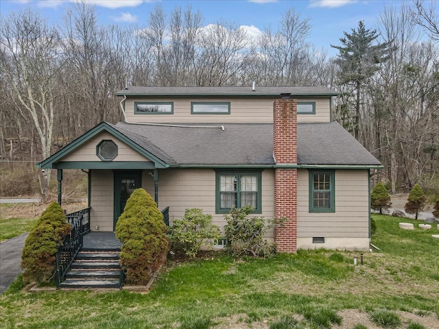 traditional-style house with a front yard, roof with shingles, covered porch, and a chimney