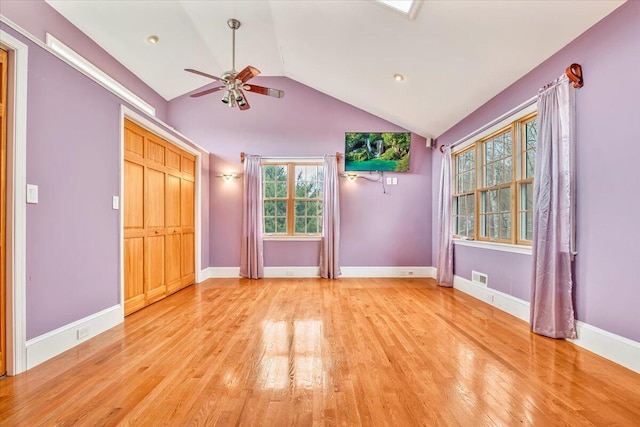 unfurnished bedroom featuring vaulted ceiling, multiple windows, and light wood-style flooring