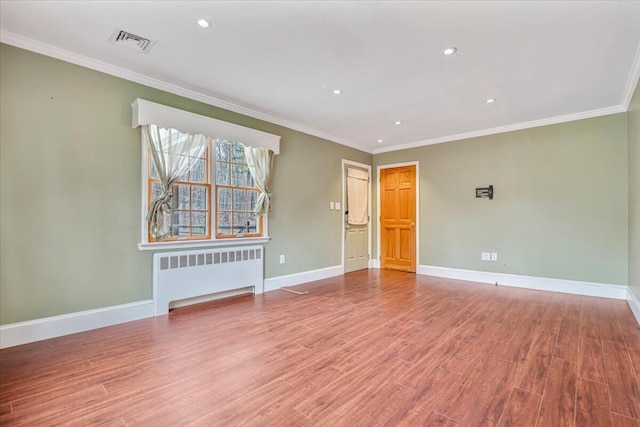 unfurnished room featuring radiator, visible vents, baseboards, ornamental molding, and wood finished floors