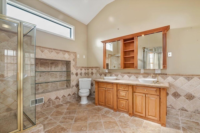 bathroom featuring tile walls, a wainscoted wall, a sink, a stall shower, and lofted ceiling