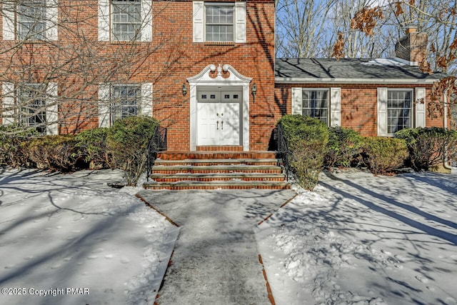 view of exterior entry featuring brick siding and a chimney