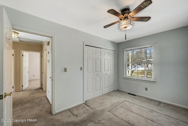 unfurnished bedroom featuring visible vents, carpet floors, a closet, baseboards, and a ceiling fan