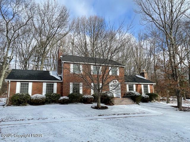 colonial home with brick siding and a chimney