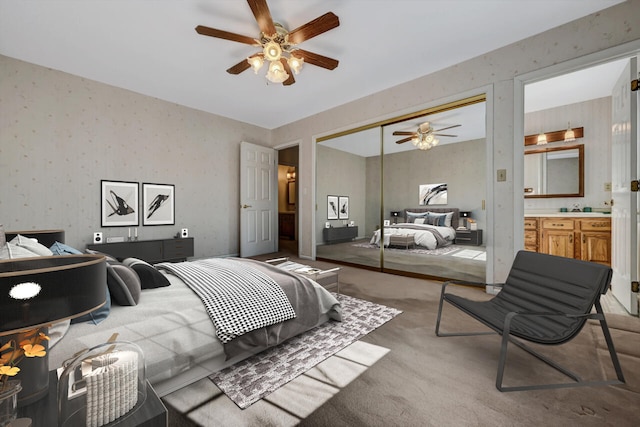 bedroom featuring ceiling fan, light colored carpet, wallpapered walls, ensuite bathroom, and a closet