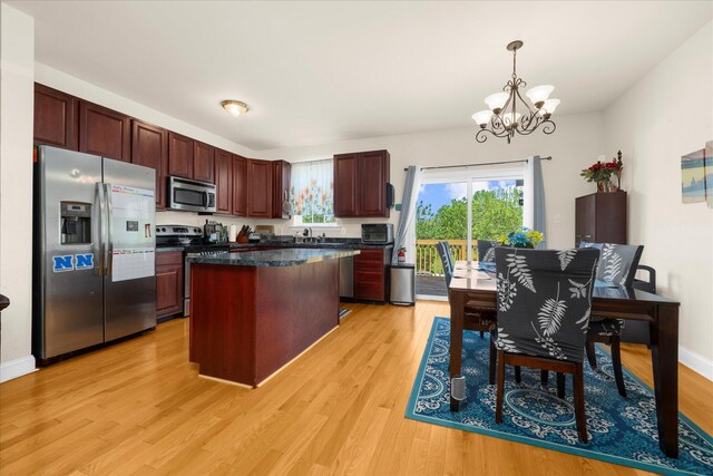 kitchen with dark countertops, a notable chandelier, appliances with stainless steel finishes, light wood-style flooring, and a center island