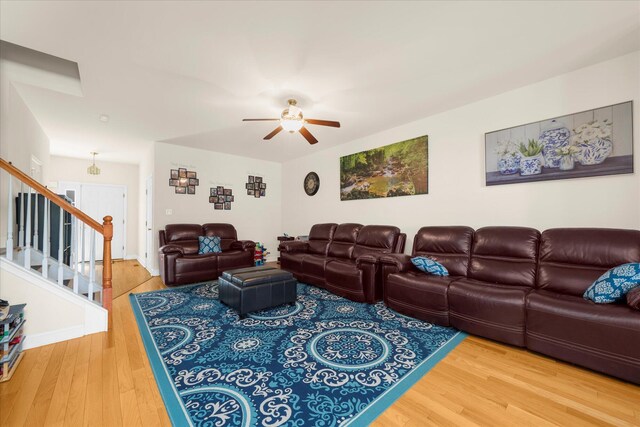 living area featuring a ceiling fan, wood finished floors, and stairway