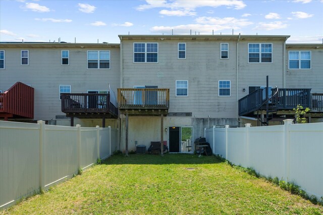rear view of house with a lawn, a fenced backyard, a wooden deck, and central air condition unit