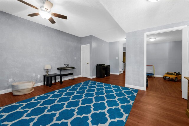 living area featuring a ceiling fan, baseboards, and wood finished floors