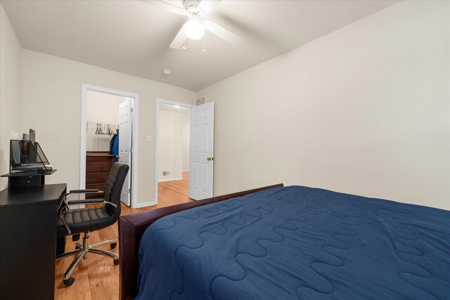 bedroom featuring baseboards, ceiling fan, wood finished floors, and a spacious closet