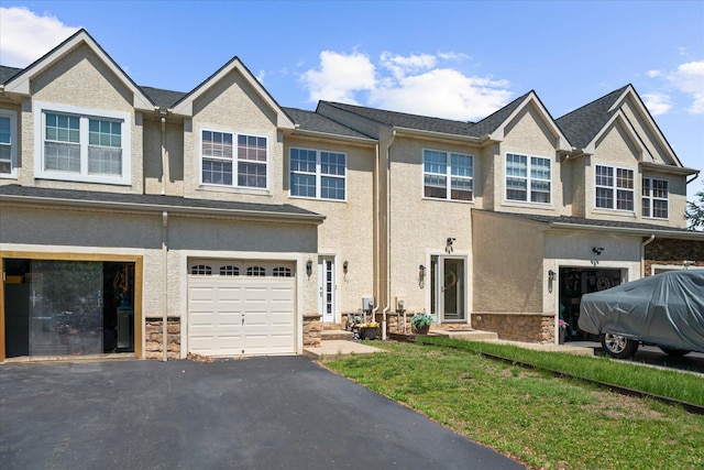 view of property with an attached garage, stone siding, and stucco siding