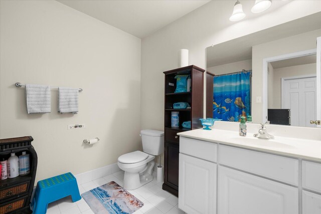 bathroom featuring curtained shower, vanity, tile patterned floors, baseboards, and toilet