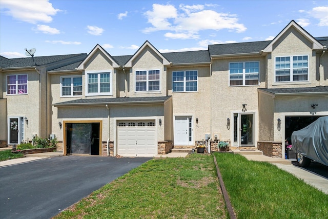 view of property featuring a garage, stucco siding, driveway, and a front lawn