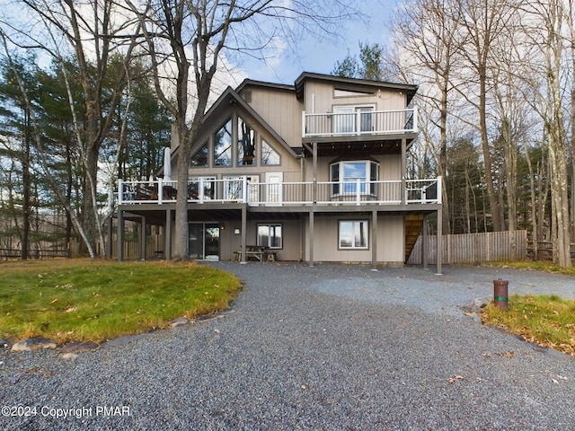 view of front of property featuring a deck, a front lawn, gravel driveway, and fence