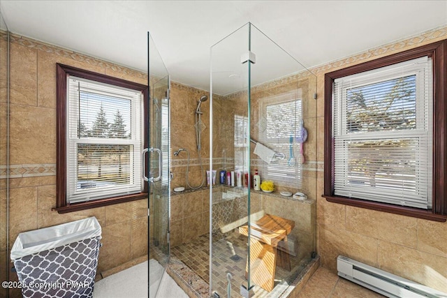 bathroom with tile walls, a baseboard heating unit, tile patterned flooring, and a shower with door