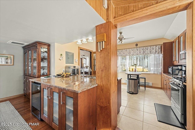 kitchen with sink, a baseboard heating unit, stainless steel appliances, light stone counters, and beverage cooler