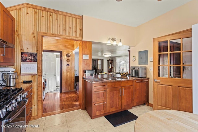 kitchen featuring washer / dryer, gas stove, sink, wood walls, and light tile patterned floors