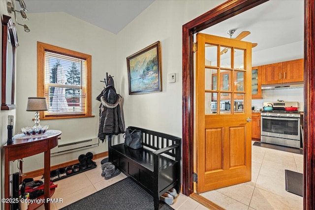 interior space with light tile patterned floors, vaulted ceiling, a baseboard radiator, and baseboards