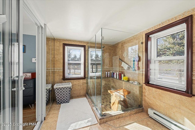 full bathroom with a stall shower, a baseboard radiator, tile patterned flooring, and tile walls