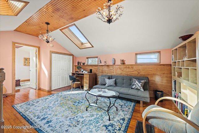 living room with lofted ceiling with skylight, wood-type flooring, and a notable chandelier