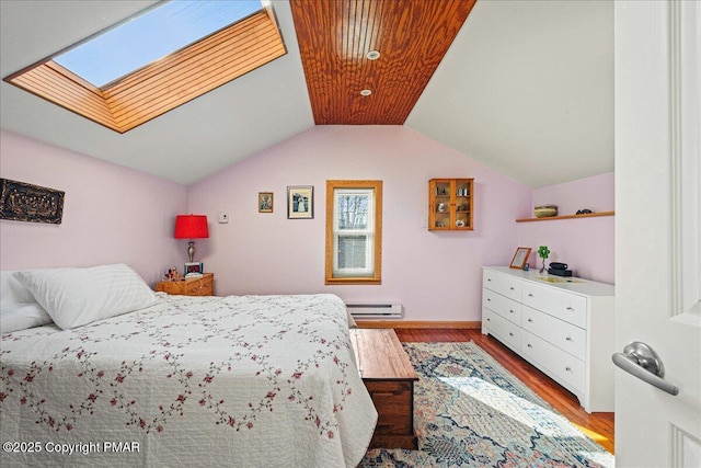 bedroom featuring light hardwood / wood-style flooring, vaulted ceiling with skylight, and baseboard heating