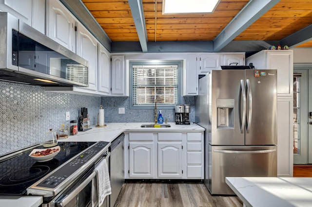 kitchen featuring a sink, beam ceiling, stainless steel appliances, white cabinetry, and backsplash