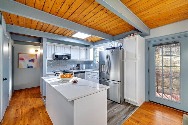 kitchen featuring appliances with stainless steel finishes, white cabinets, backsplash, and beamed ceiling