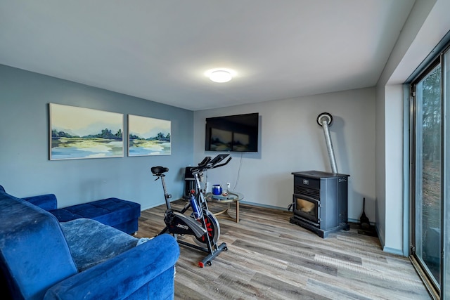 workout room with a wood stove and light wood-style floors