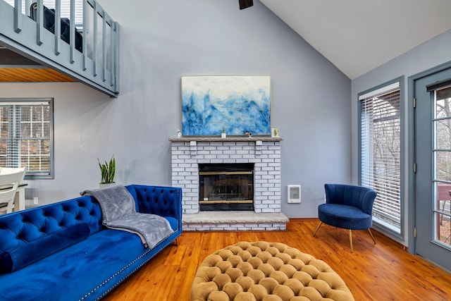 living area featuring high vaulted ceiling, a fireplace, and wood finished floors