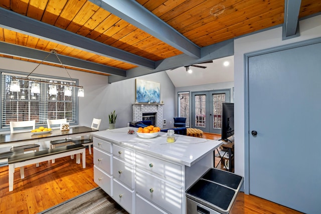 kitchen with beam ceiling, wood finished floors, a center island, and white cabinets