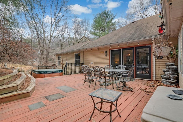 deck featuring outdoor dining space and a covered hot tub