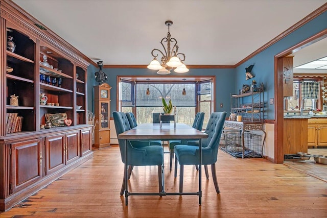 dining space with light wood-type flooring, baseboards, an inviting chandelier, and ornamental molding