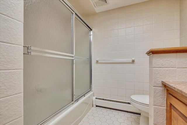 bathroom with vanity, tile patterned flooring, a baseboard heating unit, tile walls, and combined bath / shower with glass door