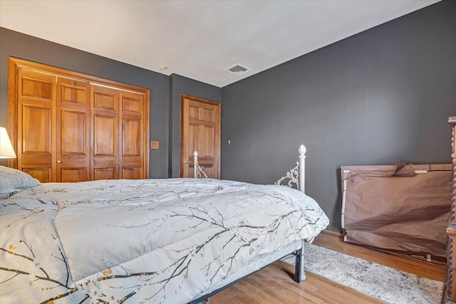 bedroom with a closet, visible vents, and wood finished floors