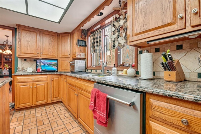 kitchen featuring light stone counters, brick floor, a sink, dishwasher, and backsplash