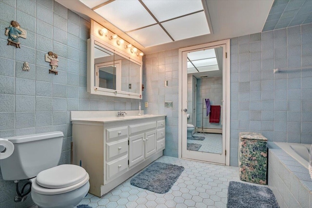 bathroom with tile patterned flooring, toilet, baseboard heating, tiled shower, and tile walls