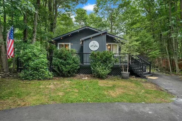 view of front of home with a deck and a front lawn