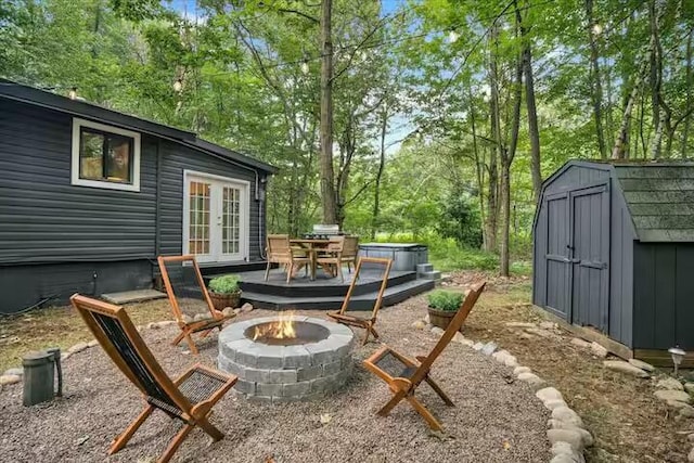 view of patio / terrace featuring an outbuilding, a shed, french doors, and an outdoor fire pit