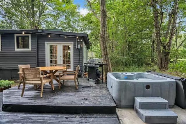 wooden deck with outdoor dining area, french doors, a hot tub, and a grill