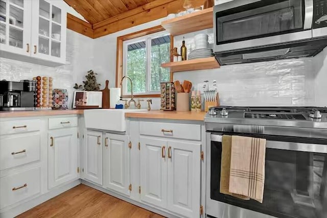 kitchen with open shelves, stainless steel appliances, decorative backsplash, and a sink