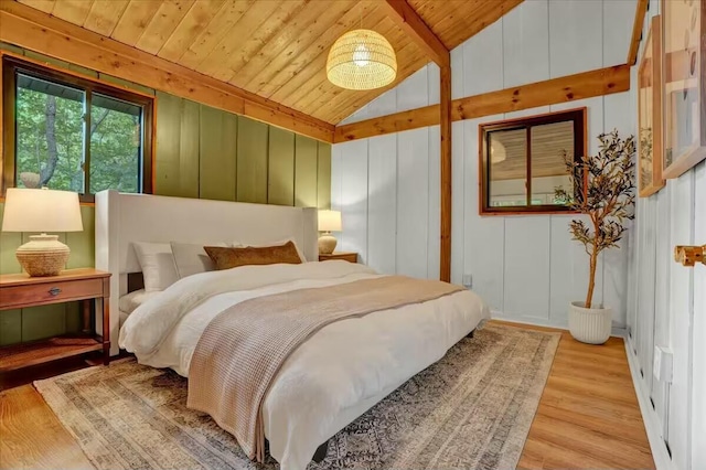 bedroom with lofted ceiling, a decorative wall, wood finished floors, and wood ceiling