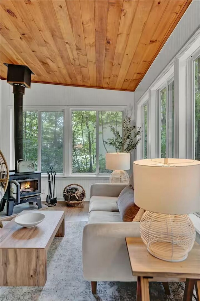 sunroom / solarium with wooden ceiling, a wood stove, and a healthy amount of sunlight