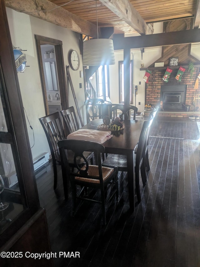 dining room featuring a baseboard radiator, a fireplace, wood finished floors, wood ceiling, and beamed ceiling