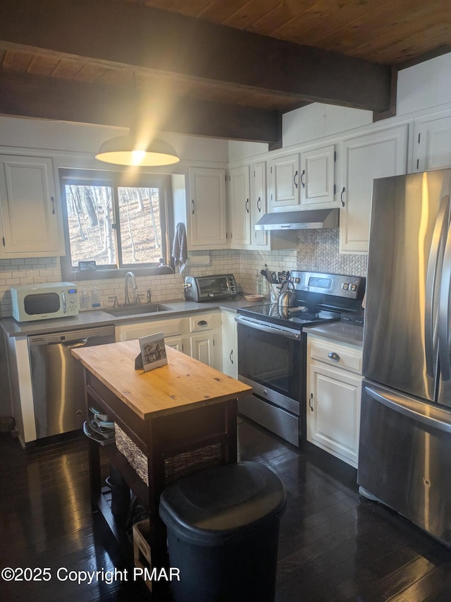 kitchen featuring under cabinet range hood, a sink, white cabinets, appliances with stainless steel finishes, and tasteful backsplash