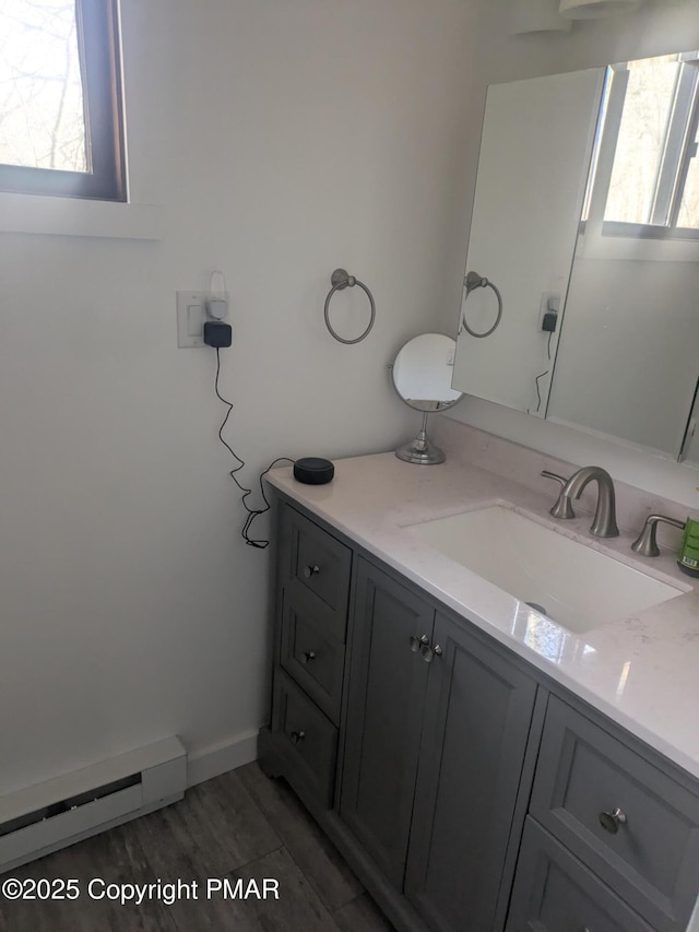 bathroom featuring a baseboard radiator, wood finished floors, vanity, and baseboards