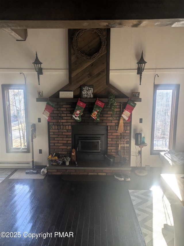 unfurnished living room with hardwood / wood-style floors, baseboard heating, a fireplace, and a healthy amount of sunlight