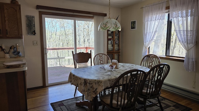 dining space with baseboards, baseboard heating, and light wood-type flooring
