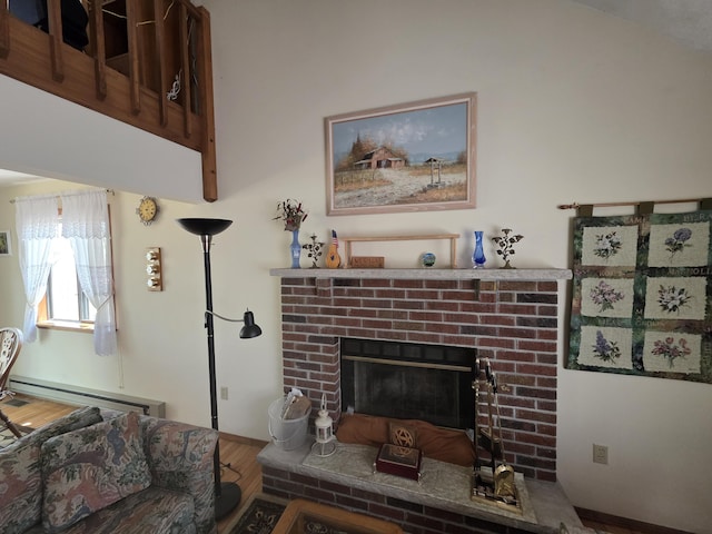 living area featuring a brick fireplace, wood finished floors, and a baseboard radiator