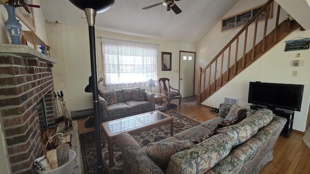 living room featuring visible vents, wood finished floors, a fireplace, stairway, and a ceiling fan