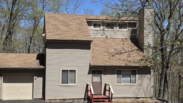 view of front facade featuring a garage, a shingled roof, and a chimney